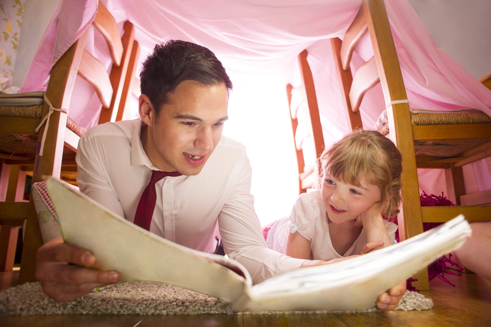 Father and daughter reading in a blanket fort